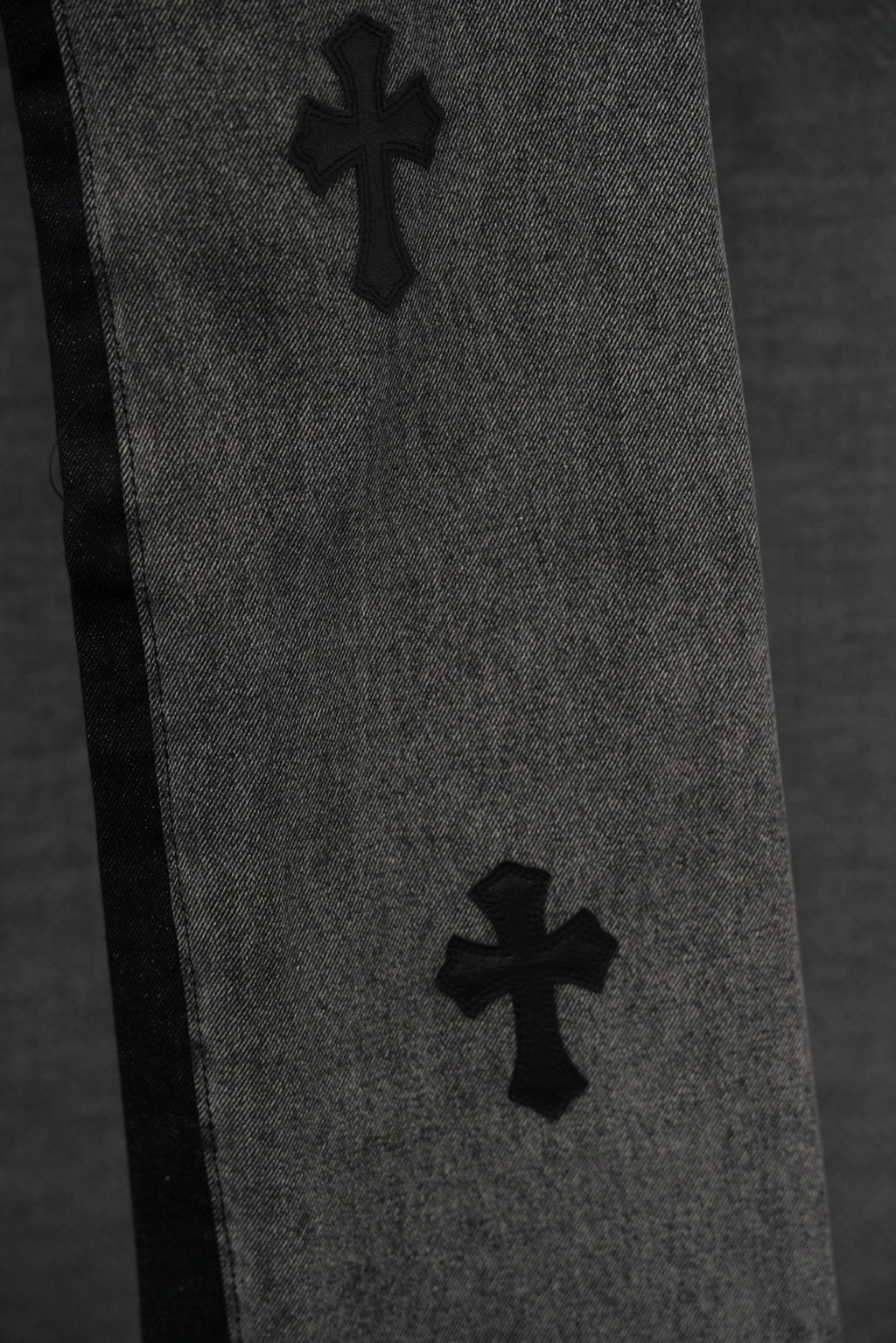 Black denim pants with two cross patches along the leg