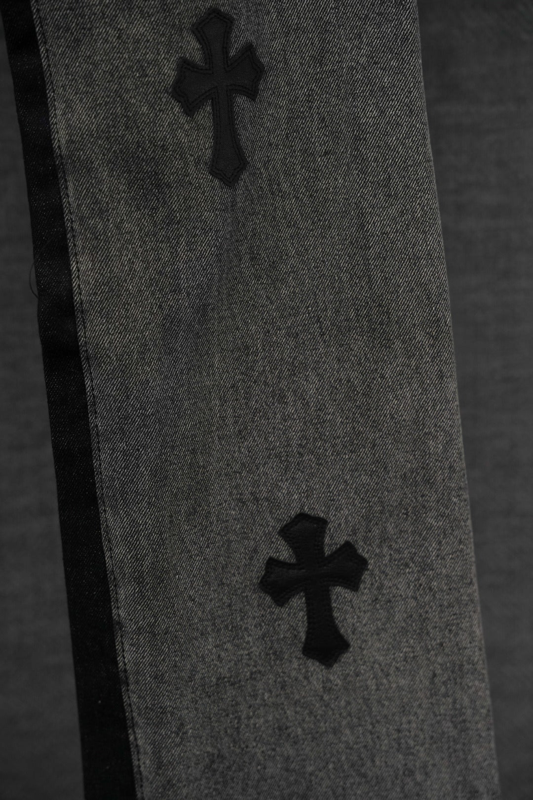 Black denim pants with two cross patches along the leg