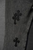 Black denim pants with raised cross patches on thigh
