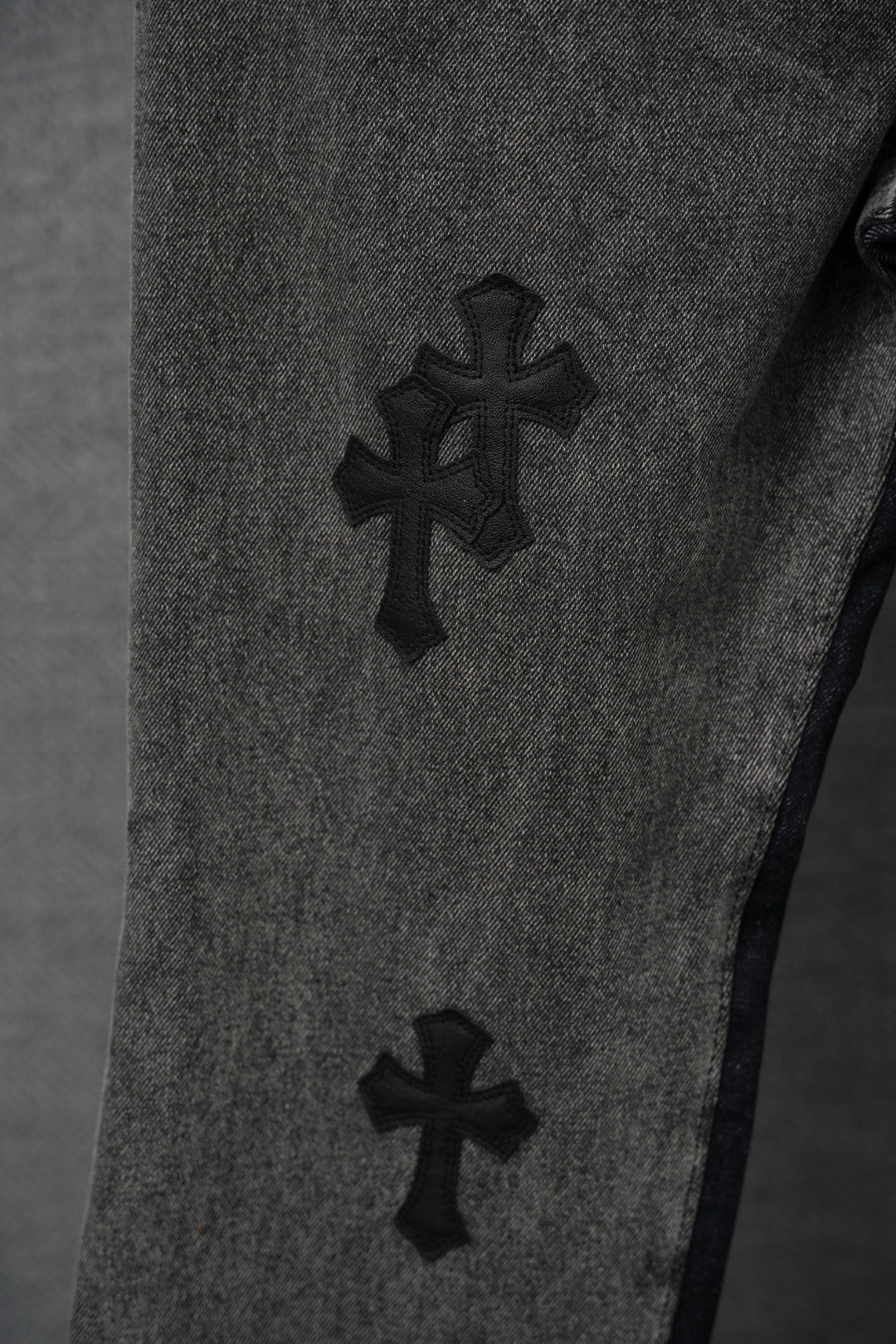 Dark denim pants with raised cross patches on the leg
