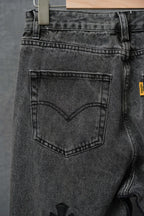 Dark denim pants, close-up of back pocket and belt loops, hanging tag