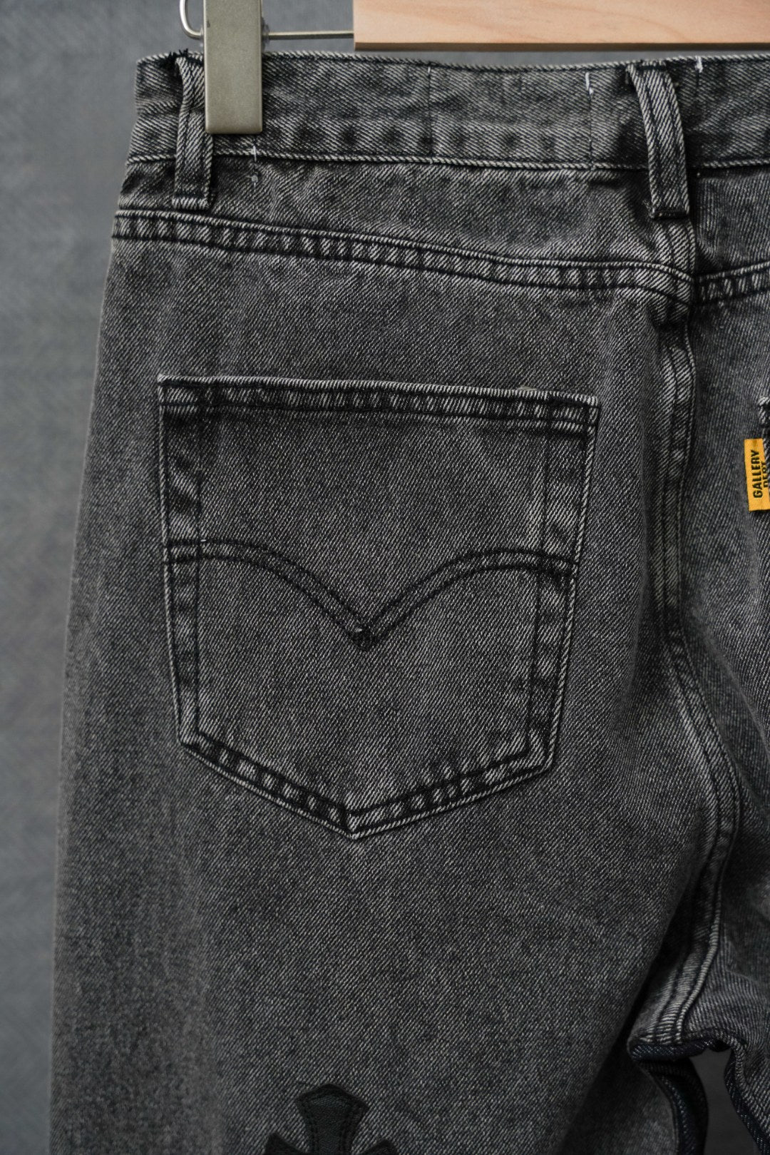 Dark denim pants, close-up of back pocket and belt loops, hanging tag