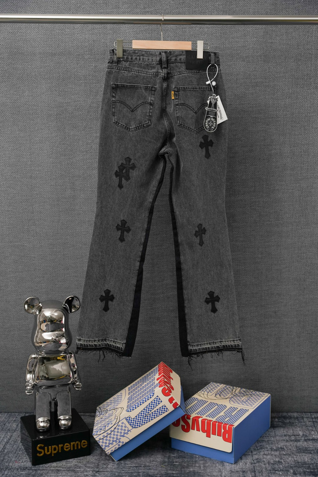 Dark denim pants with cross print, back pockets, and hanging keychain tag