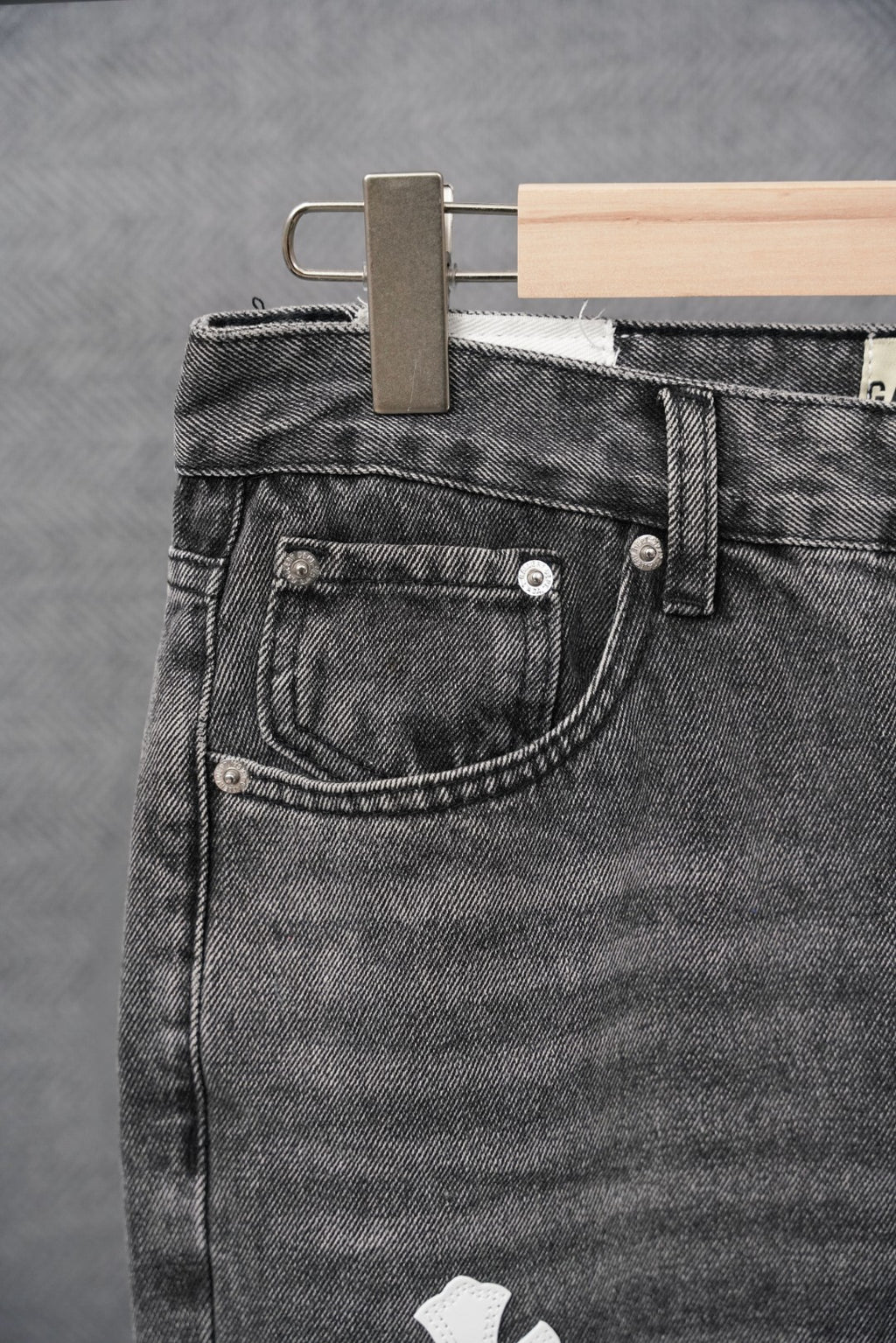 Black denim jeans pocket with metal buttons and stitched waistband yoke
