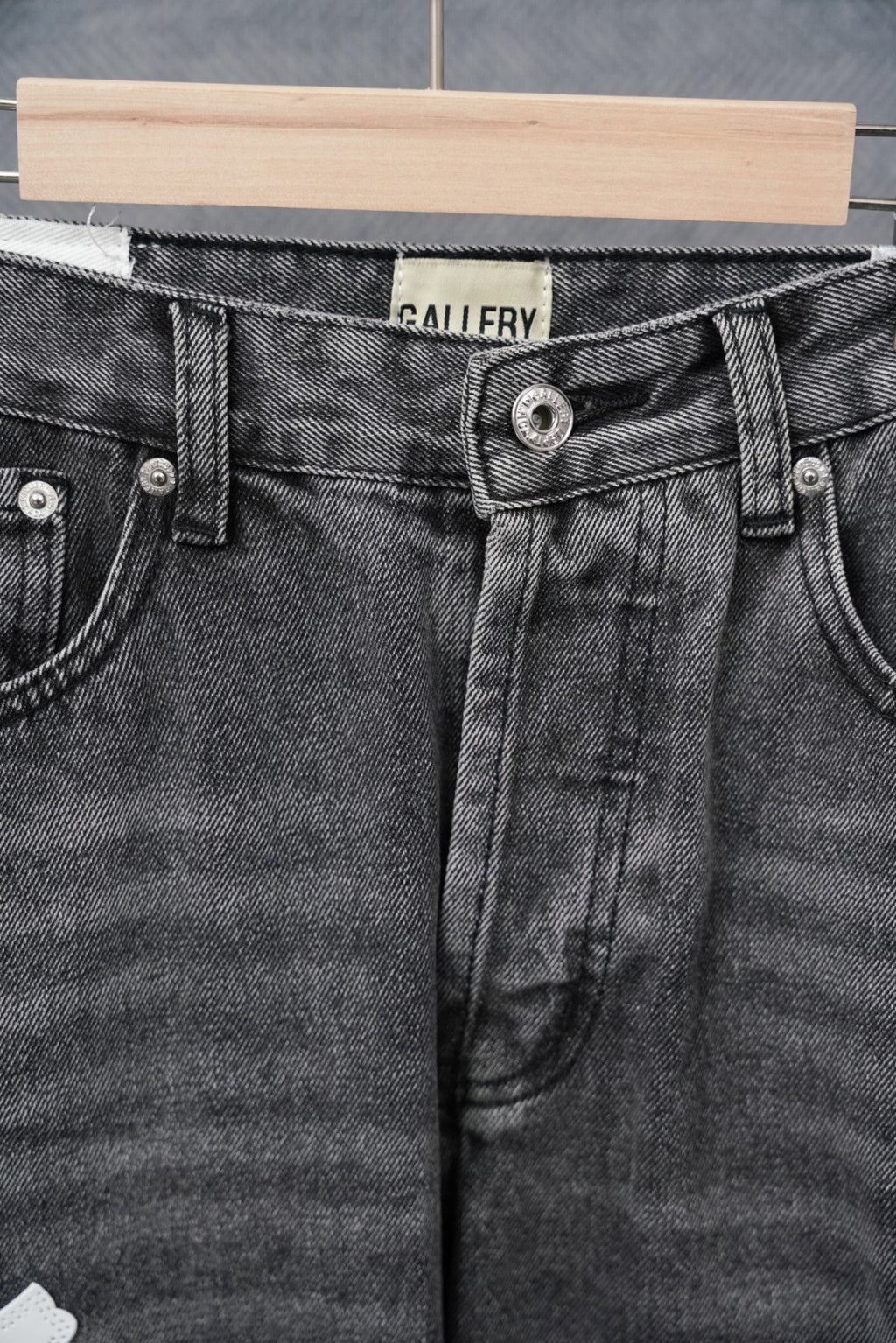 Dark gray denim pants, close-up of waistband and button fly