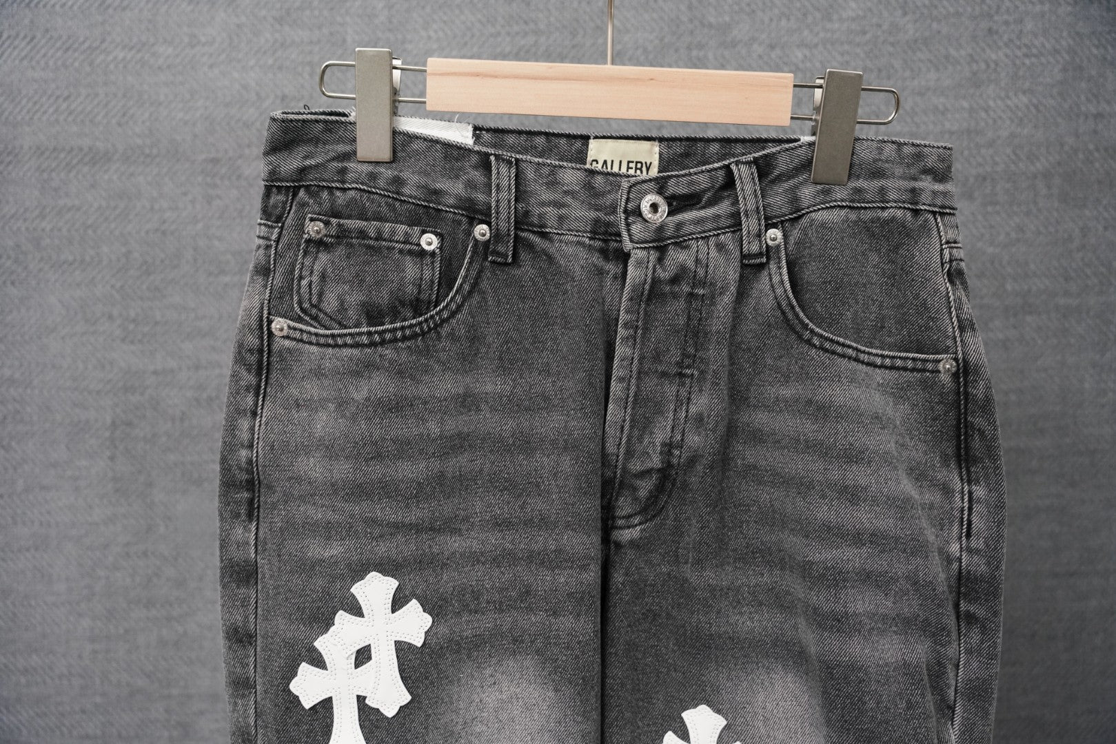 Black denim jeans with back yoke seam and white cross patch on thigh