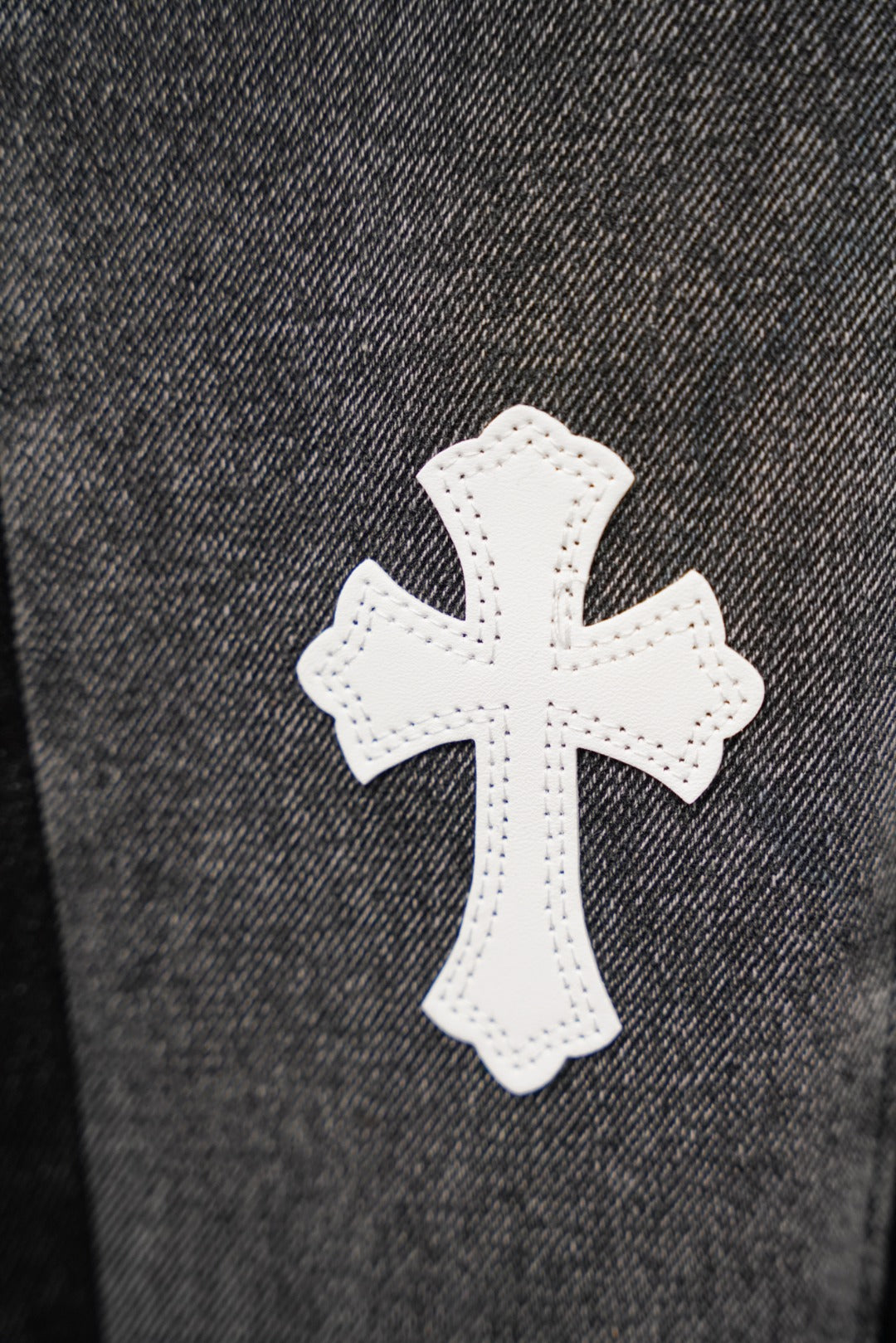 Black denim jeans with white cross patch applique on leg