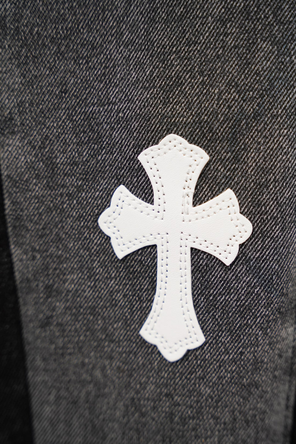 Dark gray denim with white cross patch detail, close-up