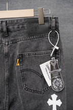 Dark denim pants with front pocket, belt loops, and white cross patch; hanging tag