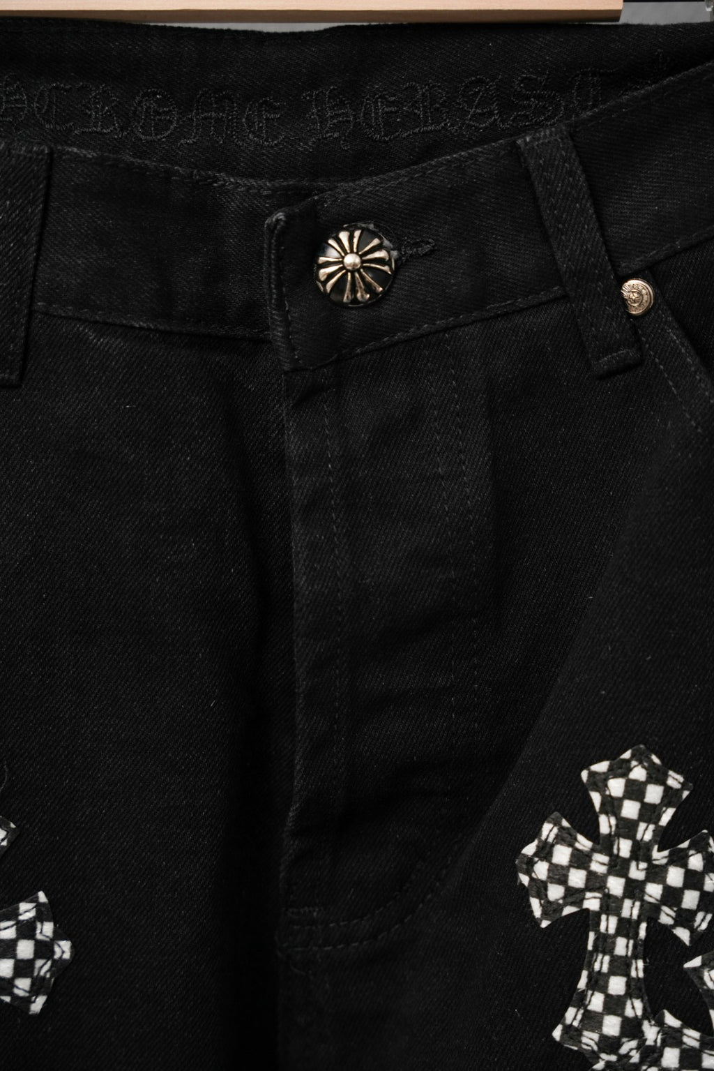 Black pants waistband close-up with decorative button and cross appliques