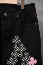 Black pants side pocket with checkered cross and pink cross appliques; metal buttons.