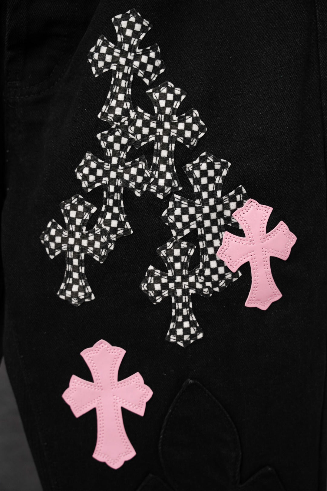 Black pants with layered checkered cross and pink cross appliques on the leg