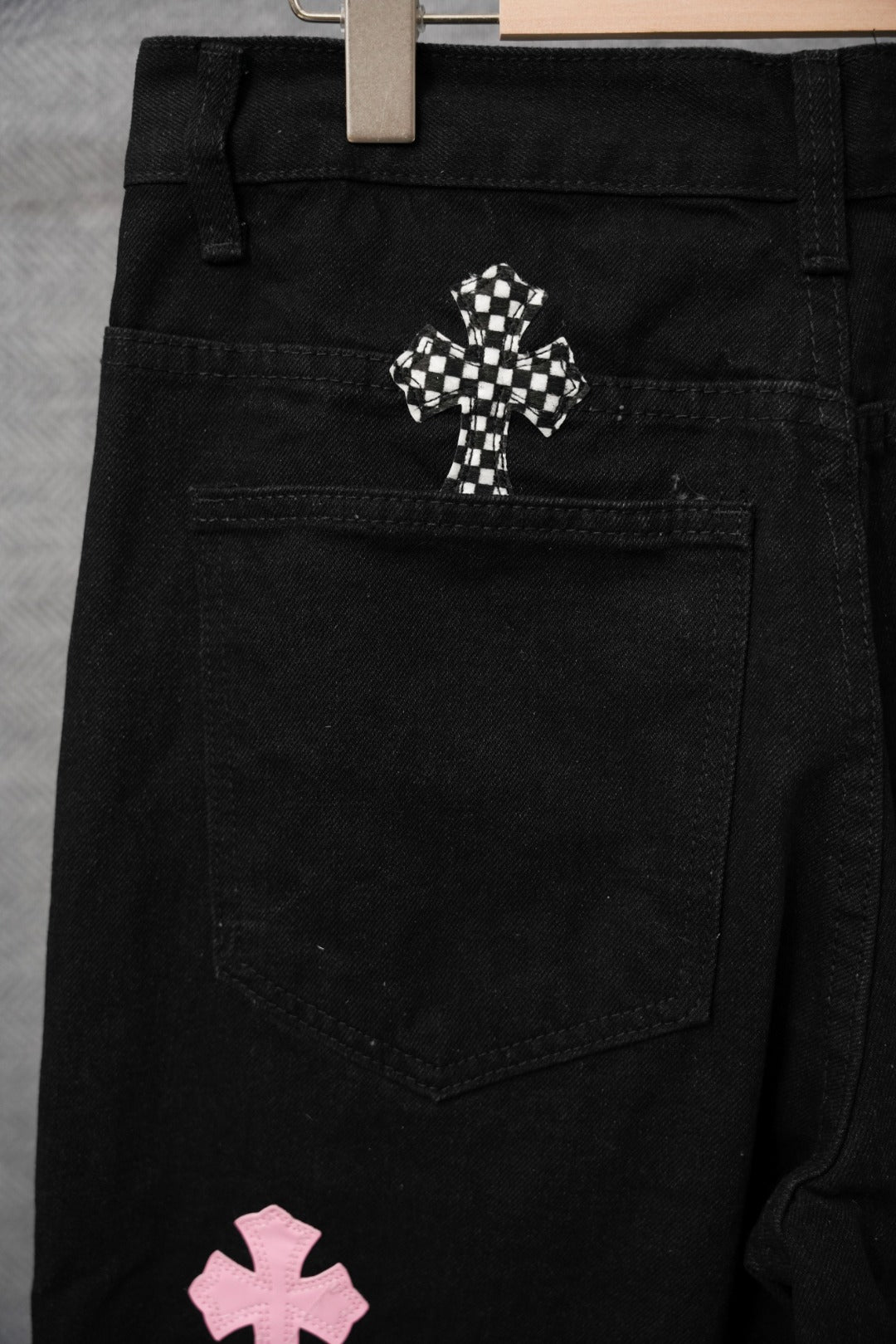 Black pants with belt loops, front pockets, and checkered decorative patch
