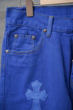 Blue pants close-up of front waistband and embroidered cross applique on leg