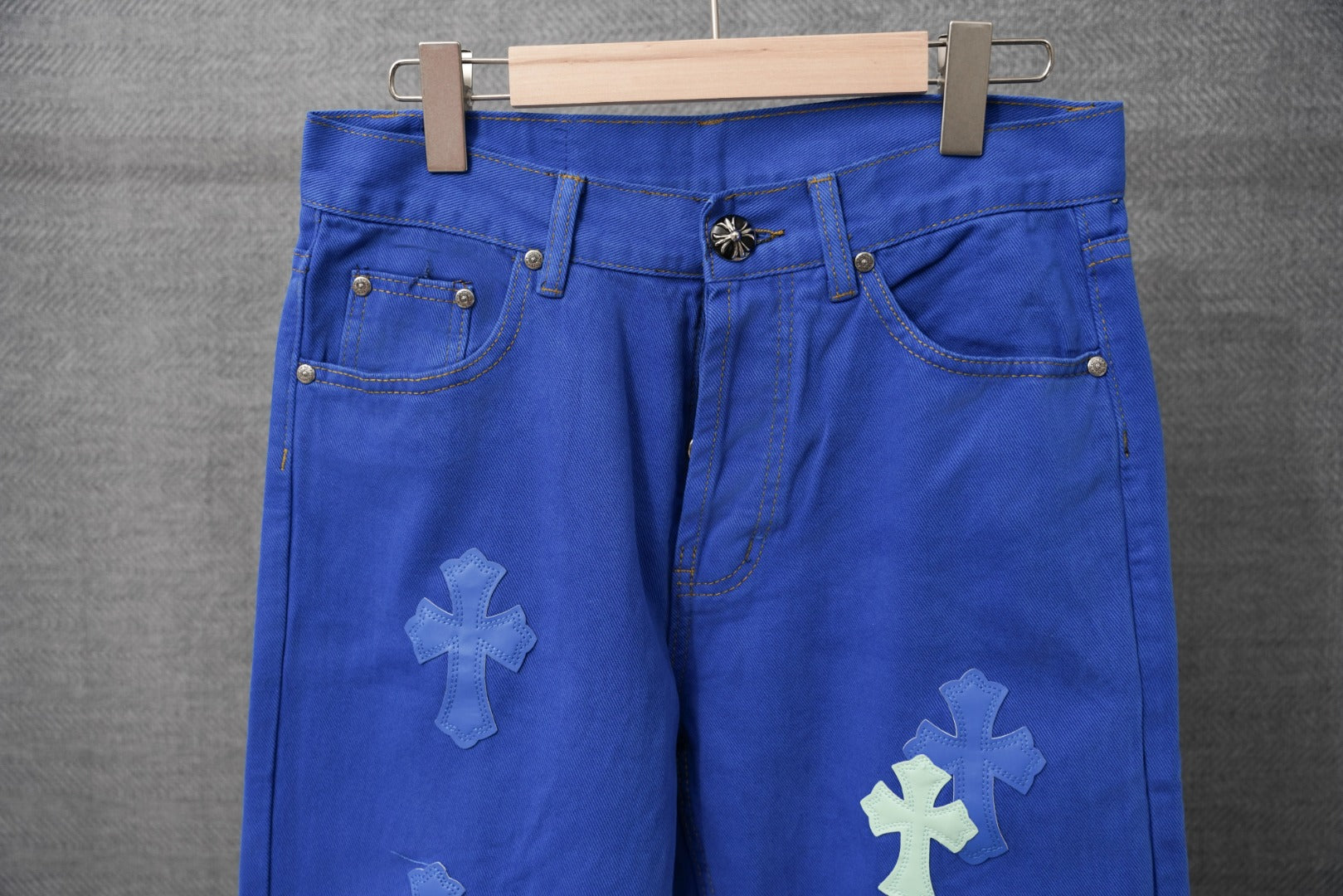 Blue pants front view with metal buttons and embroidered cross patches