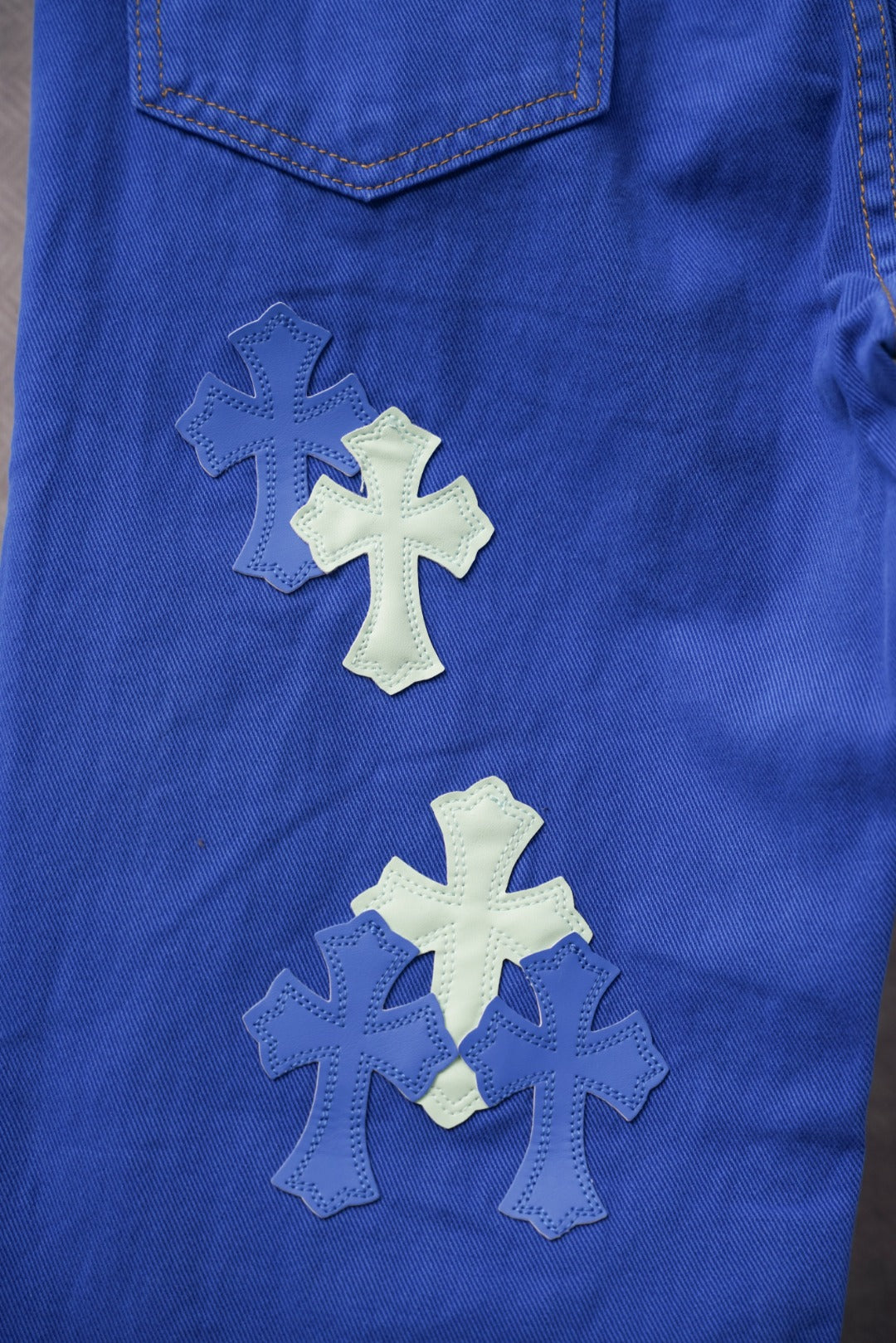 Chrome pants in blue with multiple cross applique patches near the pocket