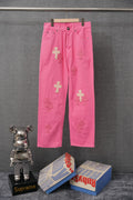 Pink denim pants with cross applique patches and front button closure