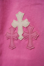 Pink denim pants with large cross applique detail on leg