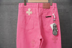 Pink pants hung for display, with cross appliques and front pockets