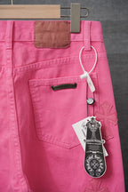 Pink pants front with belt loops, zip fly, and cross applique near pocket