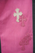 Pink chrome pants with three cross-shaped embroidered appliques on the fabric.