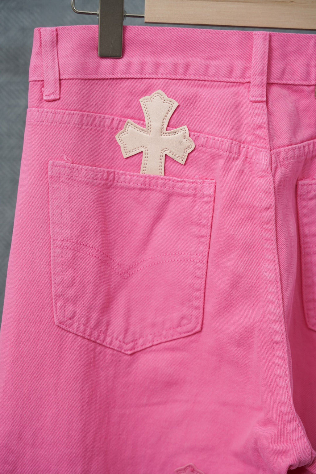 Pink chrome pants with front pockets and large cross appliques near the hem.