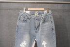 Light wash denim pants with button fly and white cross patches on legs