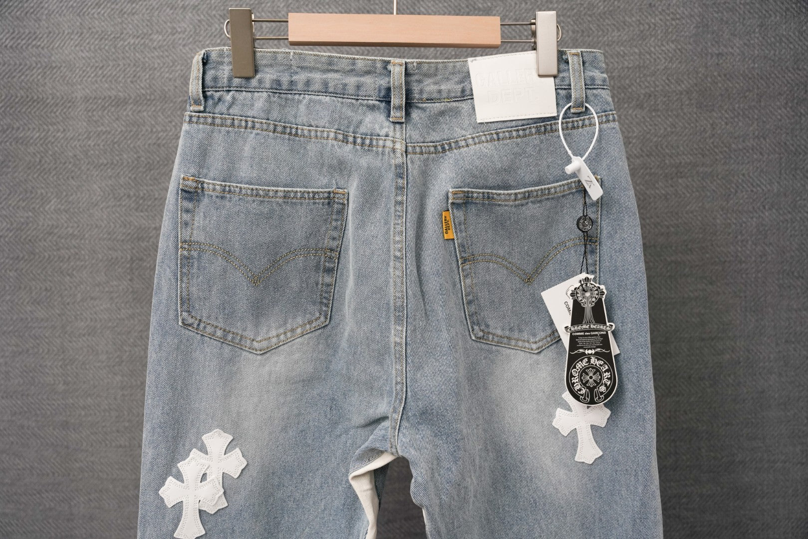 Light wash denim pants with back pockets, keychain charm, and white cross patch