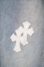 Light wash denim pants fabric with a white cross applique