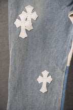 Light blue denim pants front with two white cross patches on the leg