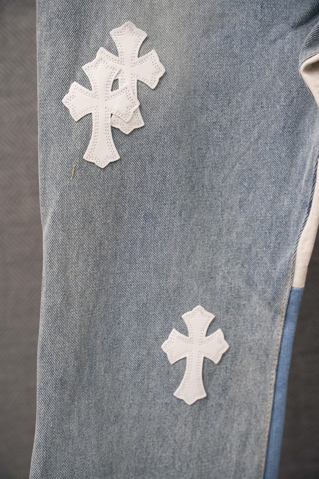 Light blue denim pants with white cross applique patches on leg
