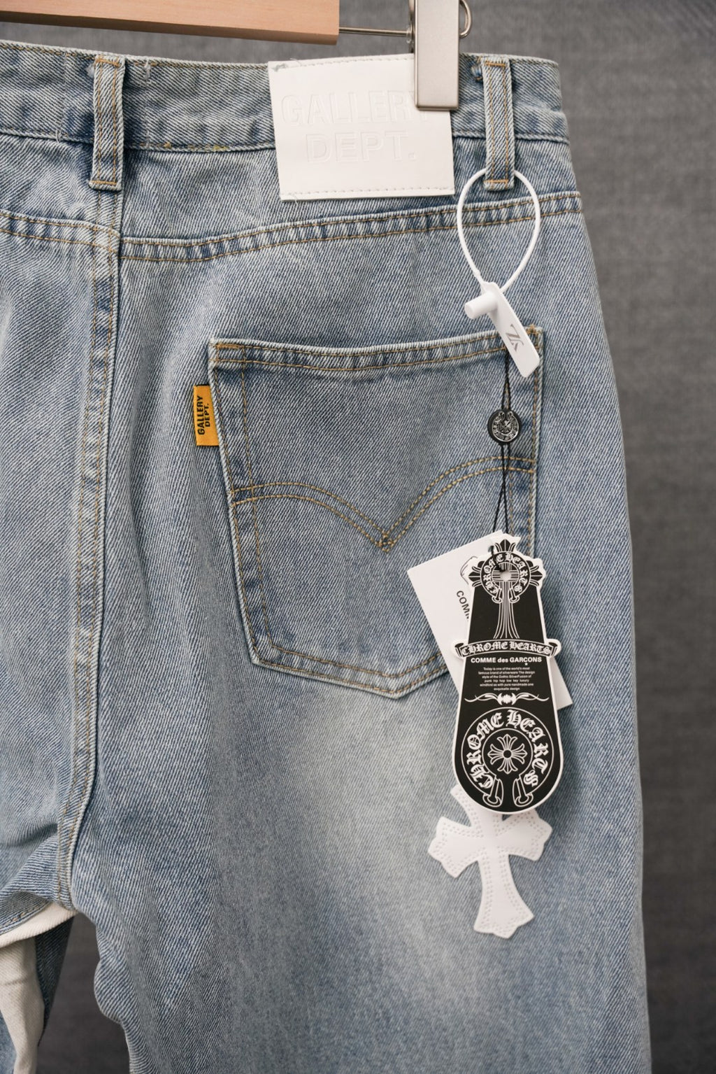 Light blue denim pants with front cross patches and back tag clips