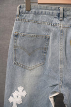 Light blue denim pants with stitched patch pocket and white cross applique detail
