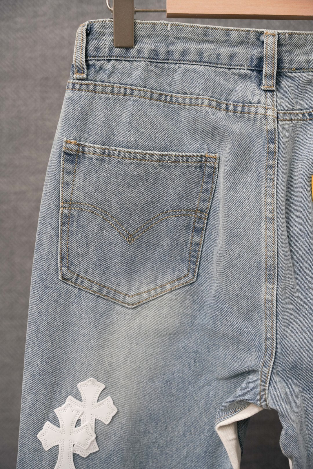 Light blue denim pants with visible front pocket and cross applique patch