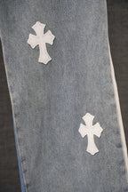 Light blue denim pants front with white cross patches near the hem