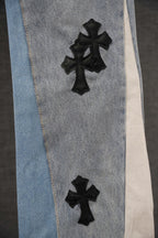 Light wash denim jeans with black cross applique on leg cuff