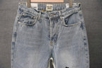 Back view of light-wash denim pants with front seam and back pockets