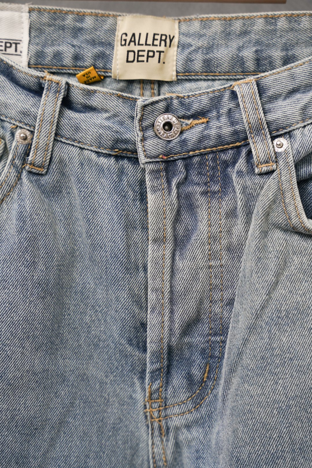 Light wash denim jeans close-up: waistband label and buttoned fly