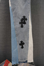 Light wash denim jeans with black cross applique and raw hem on side panel