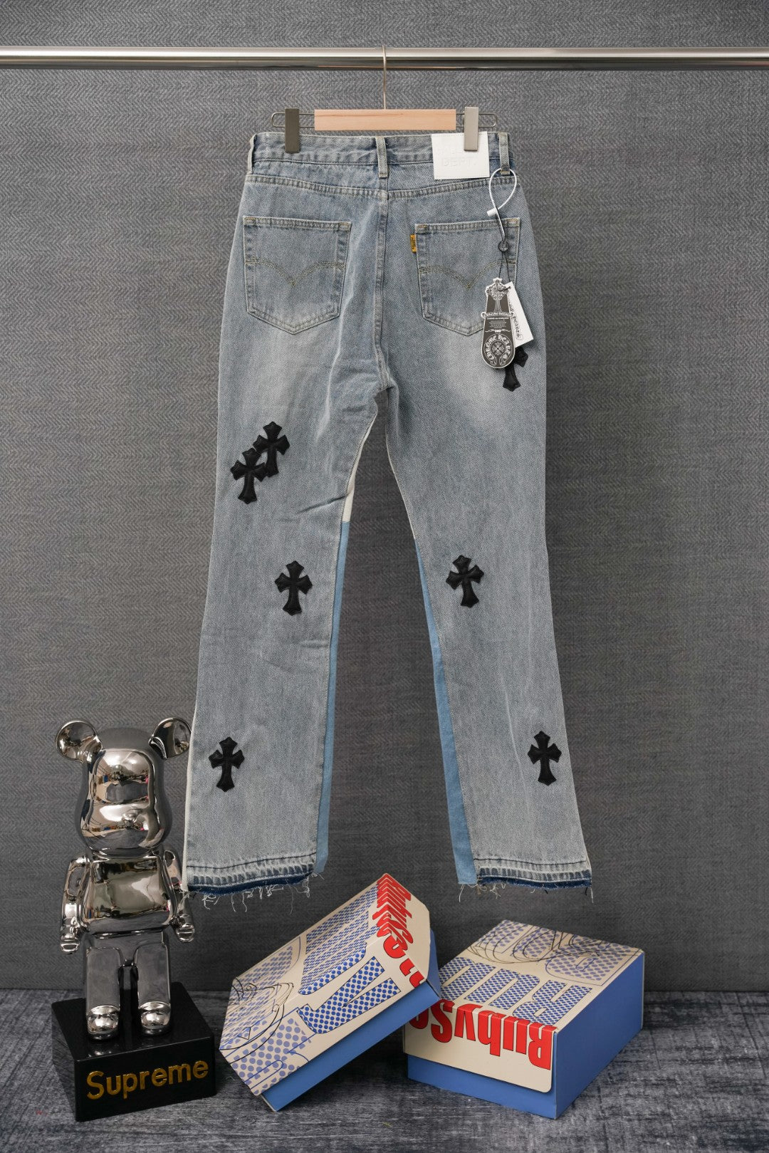 Light wash denim jeans with black cross appliques and distressed cuffs