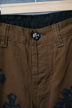 Brown pants with button waist and dark cross patch embroidery on leg