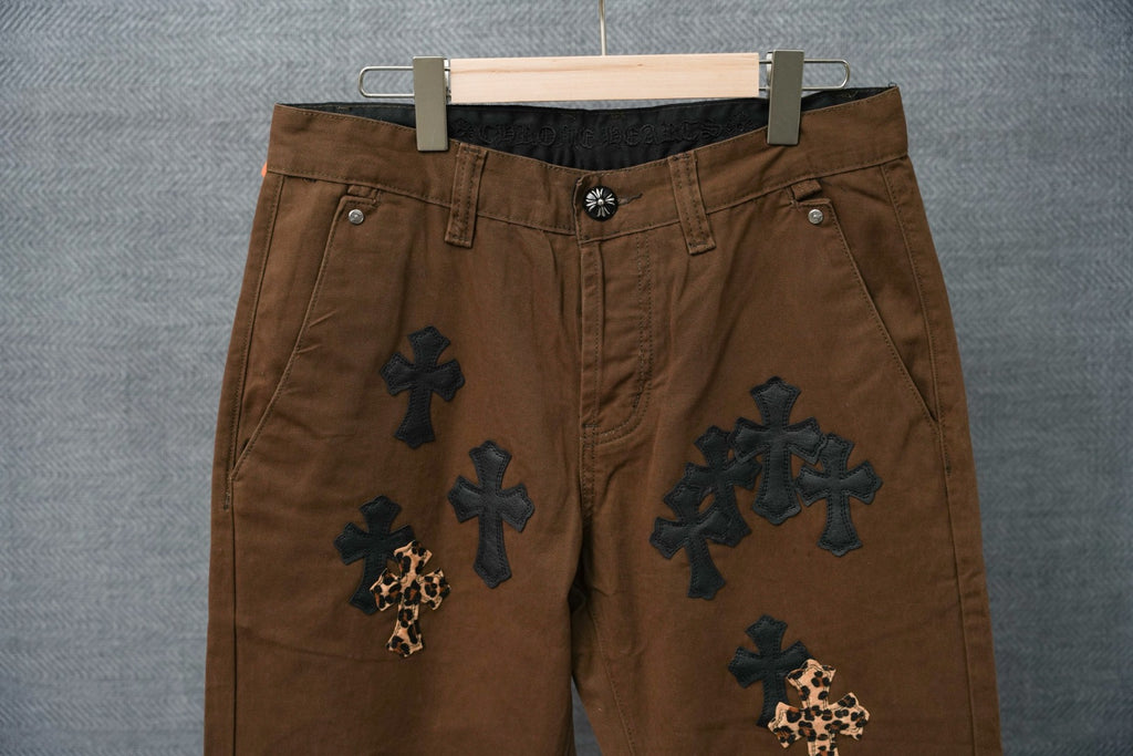 Brown chino-style pants with embroidered crosses and leopard-print cross details