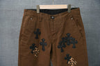 Brown pants with button fly, belt loops, and dark blue and leopard cross patches