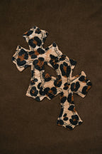 Leopard-print cross patch with dark embroidered cross designs on brown fabric