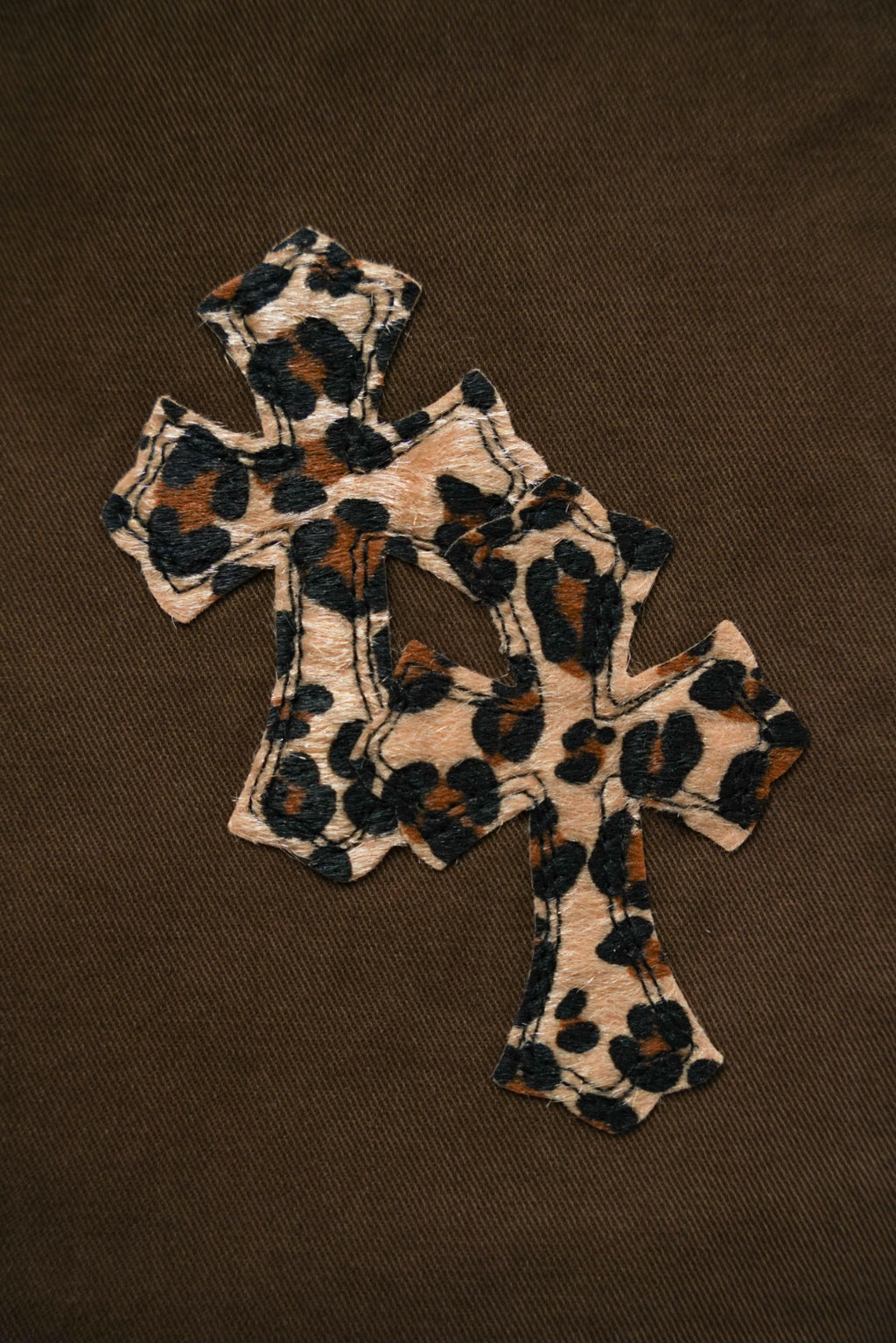 Leopard-print cross applique on brown pants