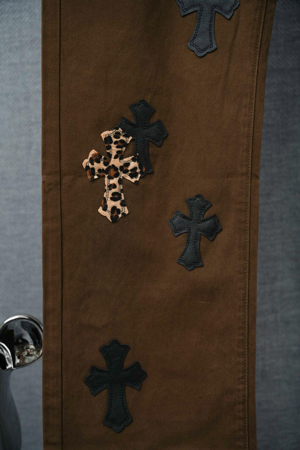 Brown pants with dark cross patches and one leopard-print cross applique