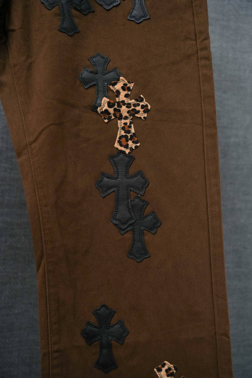 Brown pants leg with leopard-print cross applique and dark cross embroidery