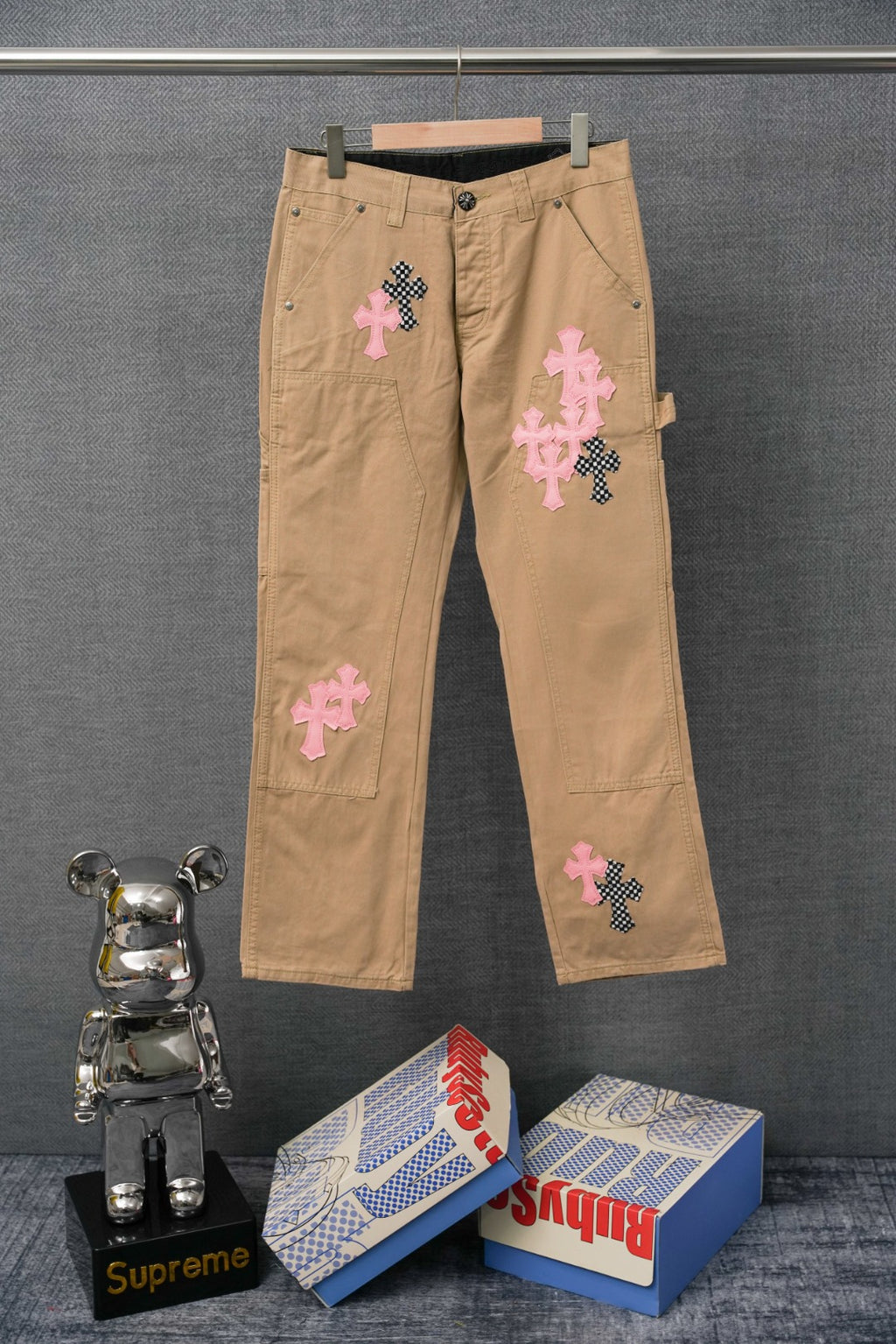 Beige cargo pants with pink and black cross patches, button fly and belt loops