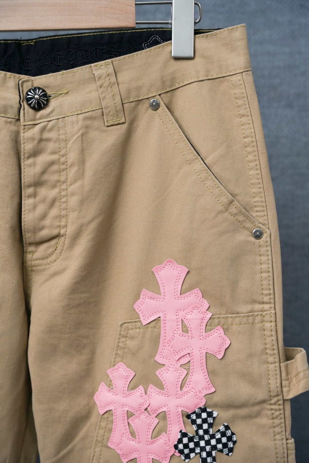 Beige cargo pants with large pink cross patch on thigh and side pocket