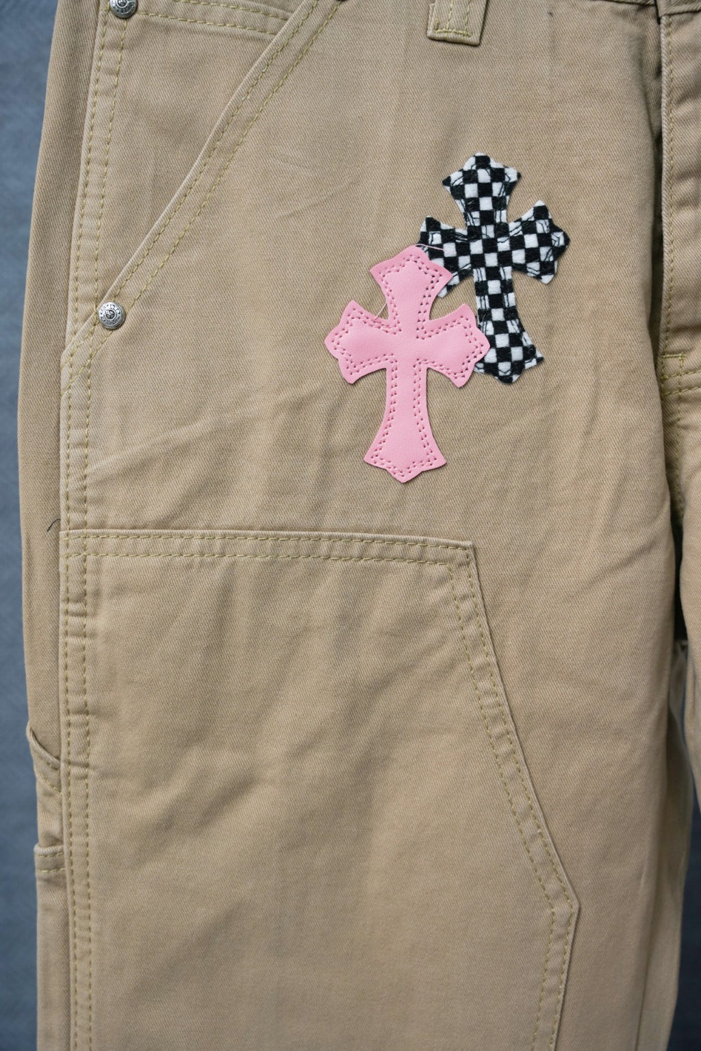 Beige cargo pants with pink and checkered cross patches on front